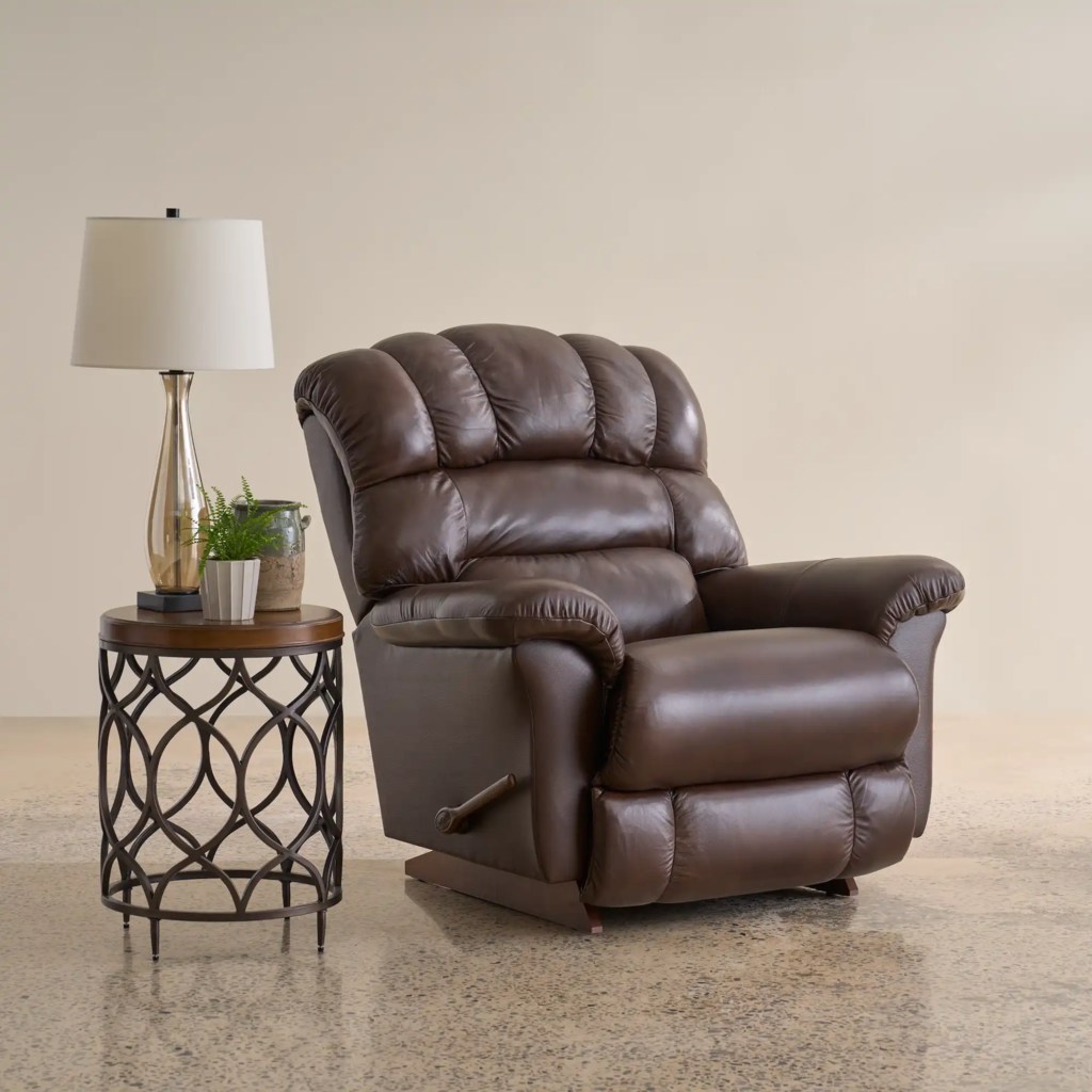 Brown leather rocking recliner beside a round side table and floor lamp