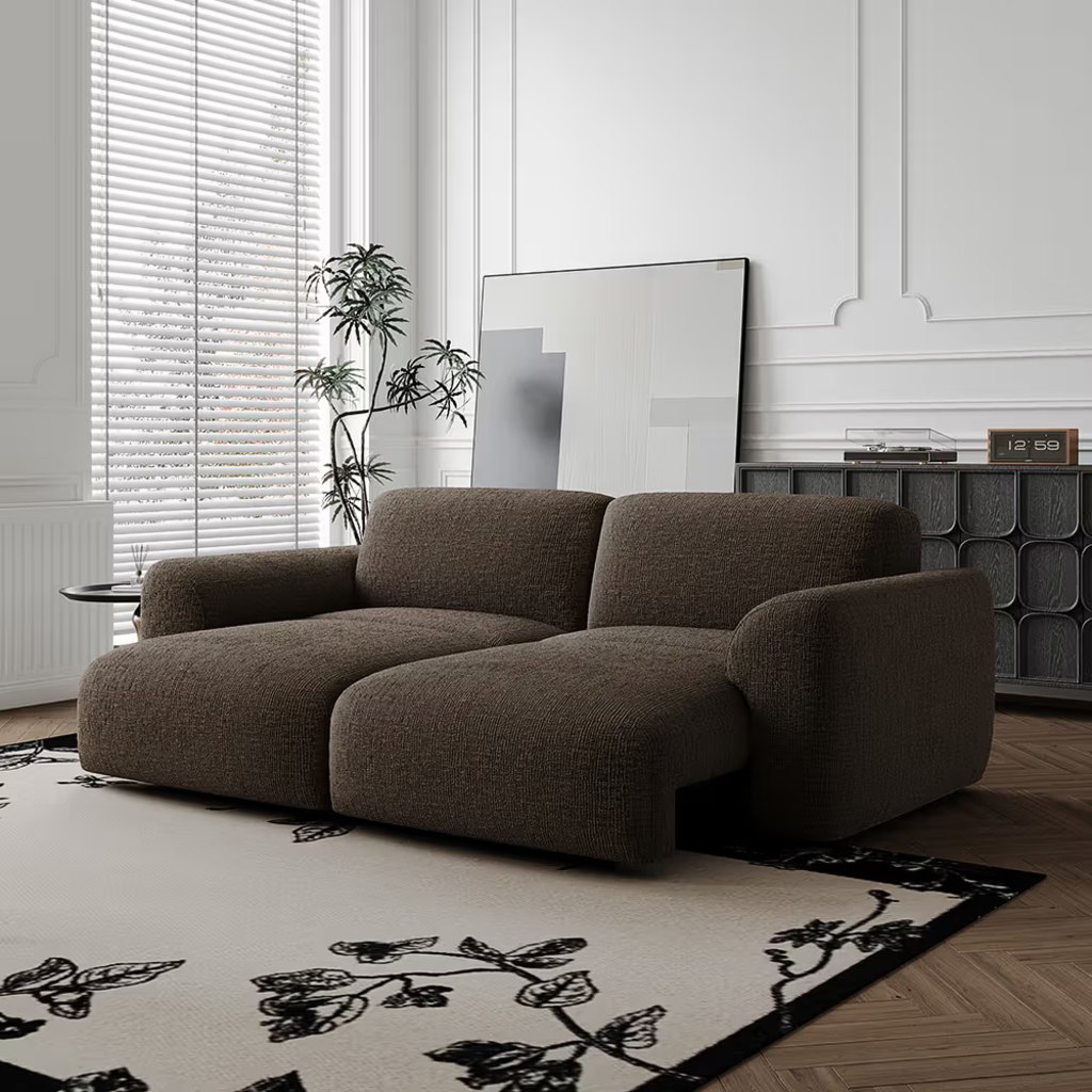 Brown two-seat power reclining sofa in a modern living room with a patterned rug and large window.