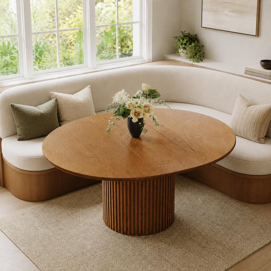 Curved banquette seating with a round wooden dining table in a bright modern dining nook.