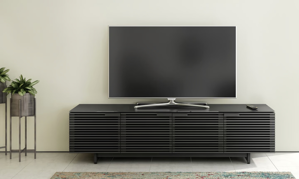 Minimalist living room with a black TV stand, flat-screen television, indoor plants, and clean modern interior design.