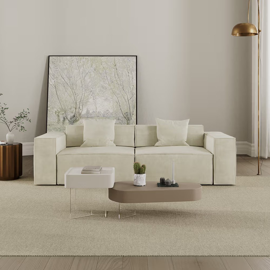 Cream modular sofa with two seats, wide square arms, and accent pillows in a modern neutral living room.