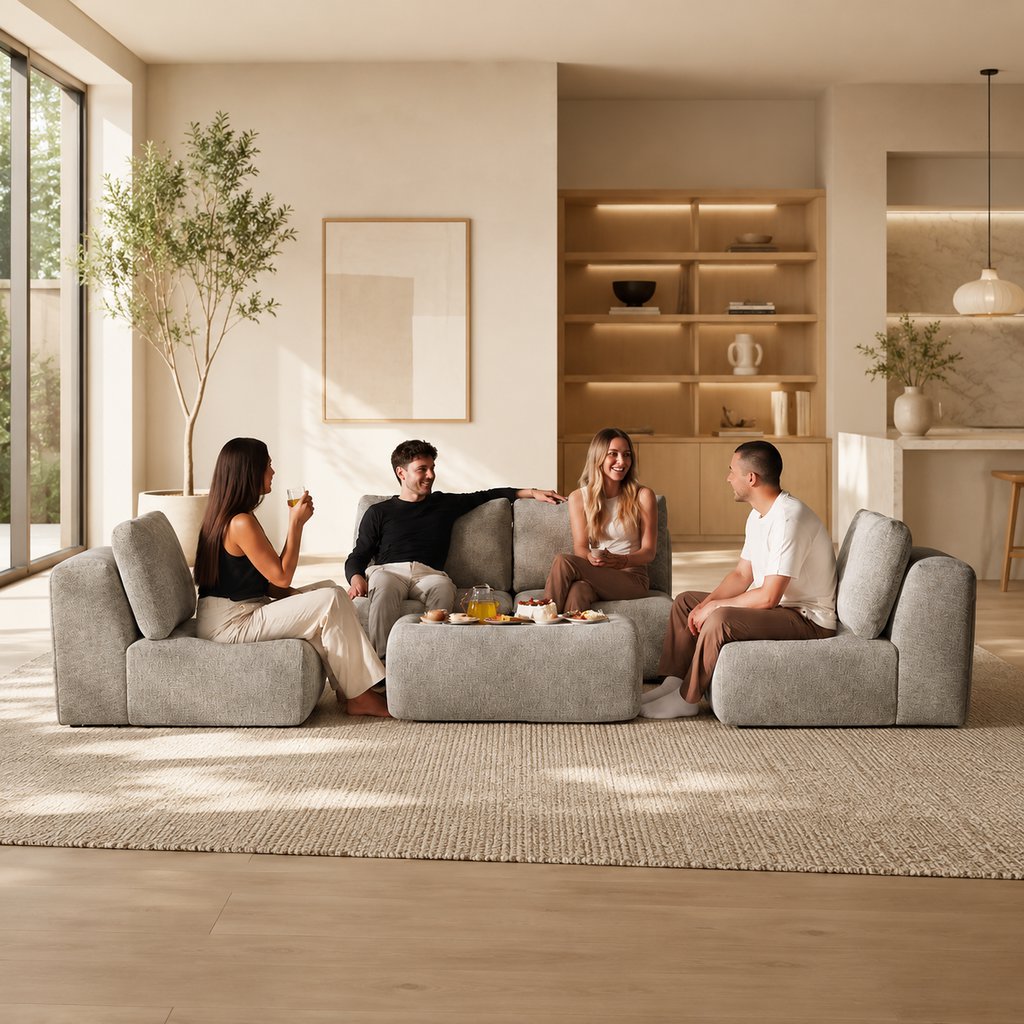 Friends relaxing on a modular gray sofa with ottoman in a bright modern living room.