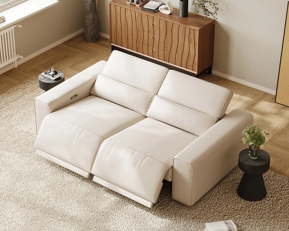 Beige dual-power reclining loveseat with both footrests extended in a modern living room with wood flooring and side tables.