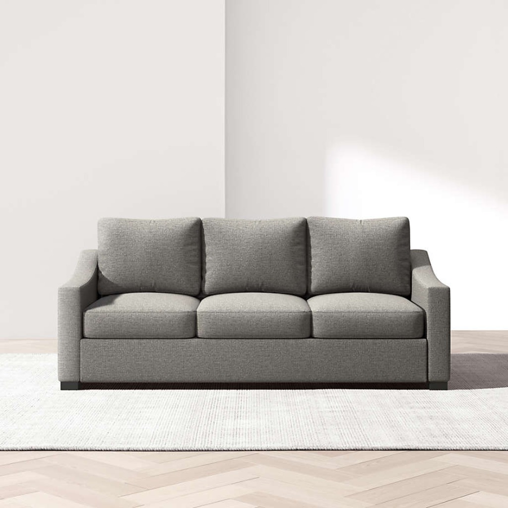 Gray upholstered sleeper sofa with three seat and back cushions in a minimalist room with neutral walls and a light rug.