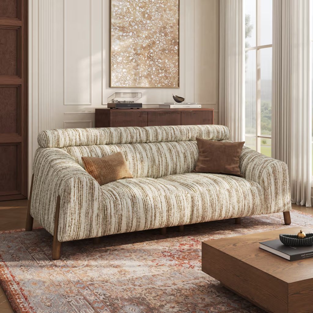 Striped high-back loveseat in a bright living room with a wooden coffee table.