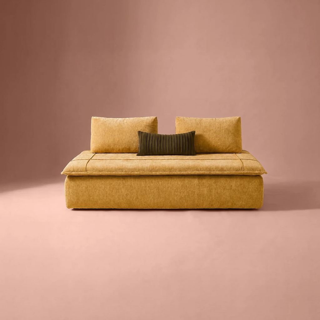 Mustard yellow low-profile sofa with movable back cushions and a lumbar pillow against a minimalist pink backdrop.