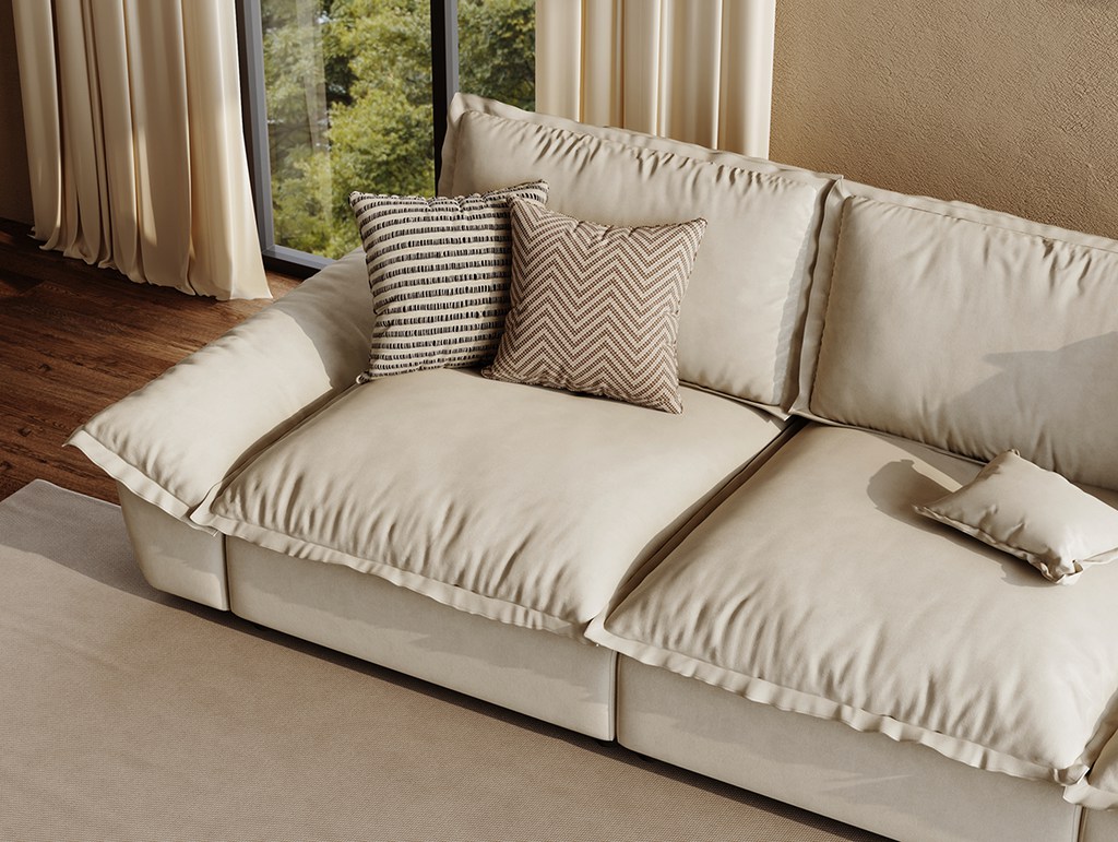 Beige deep-seat sofa with oversized cushions and patterned throw pillows beside a sunlit window.