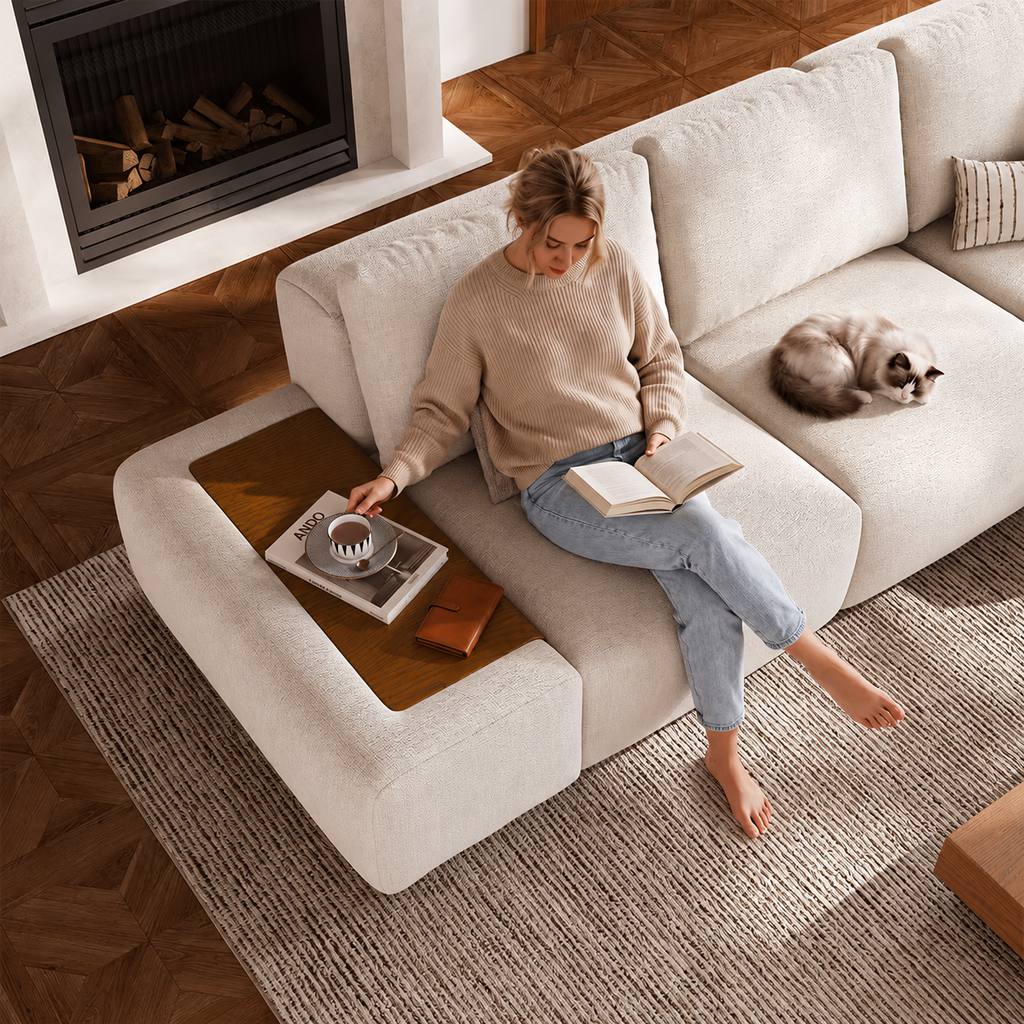 Woman reading on a white modular sofa with a cat beside her in a cozy living room.