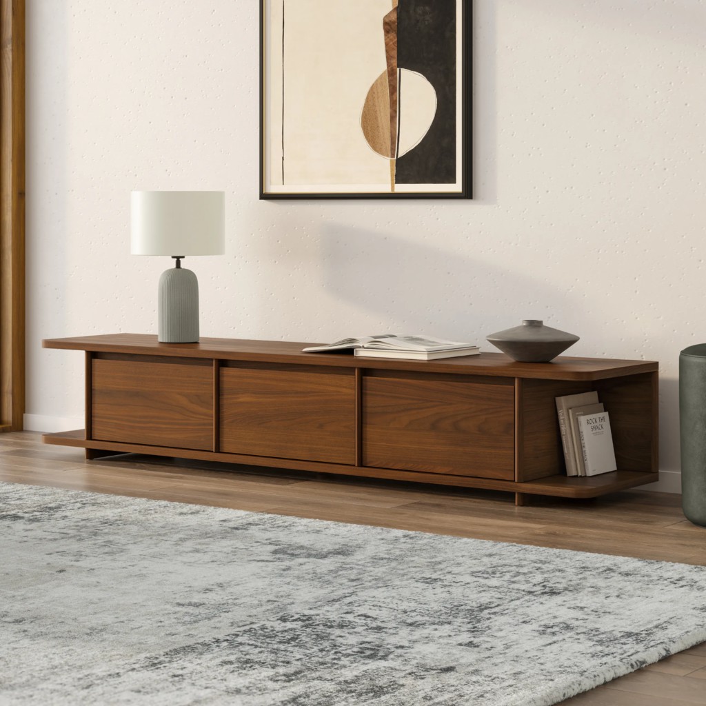 Walnut media console with three closed cabinets and open side shelving styled with a lamp, books, and minimalist decor.