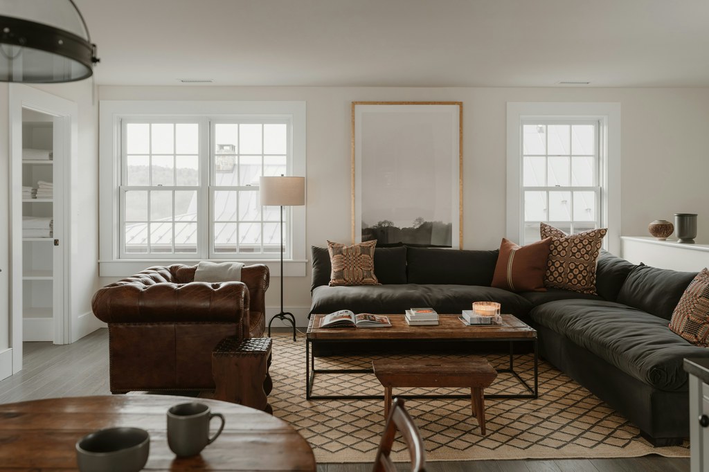Dark sectional sofa with a rectangular wood coffee table in a warm modern living room.