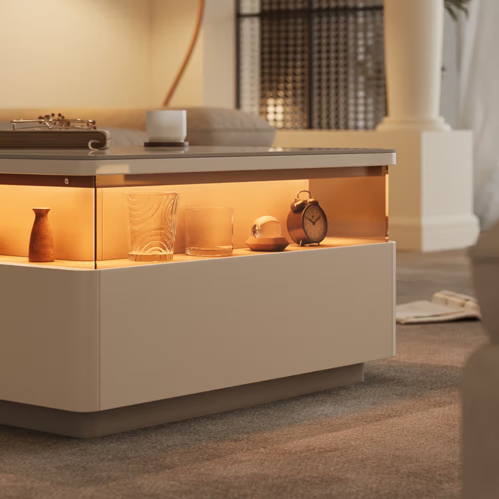 White LED coffee table with warm illuminated display storage, decorative glassware, and an alarm clock in a modern living room.