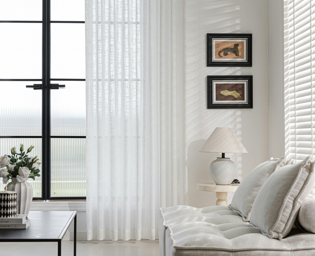 Bright light and airy living room with sheer white curtains, neutral sofa, soft cushions, and natural sunlight.