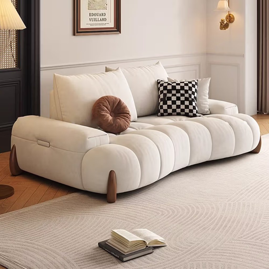 Cream deep-seat sofa with channel-tufted cushions and layered pillows in a cozy shared apartment living room.
