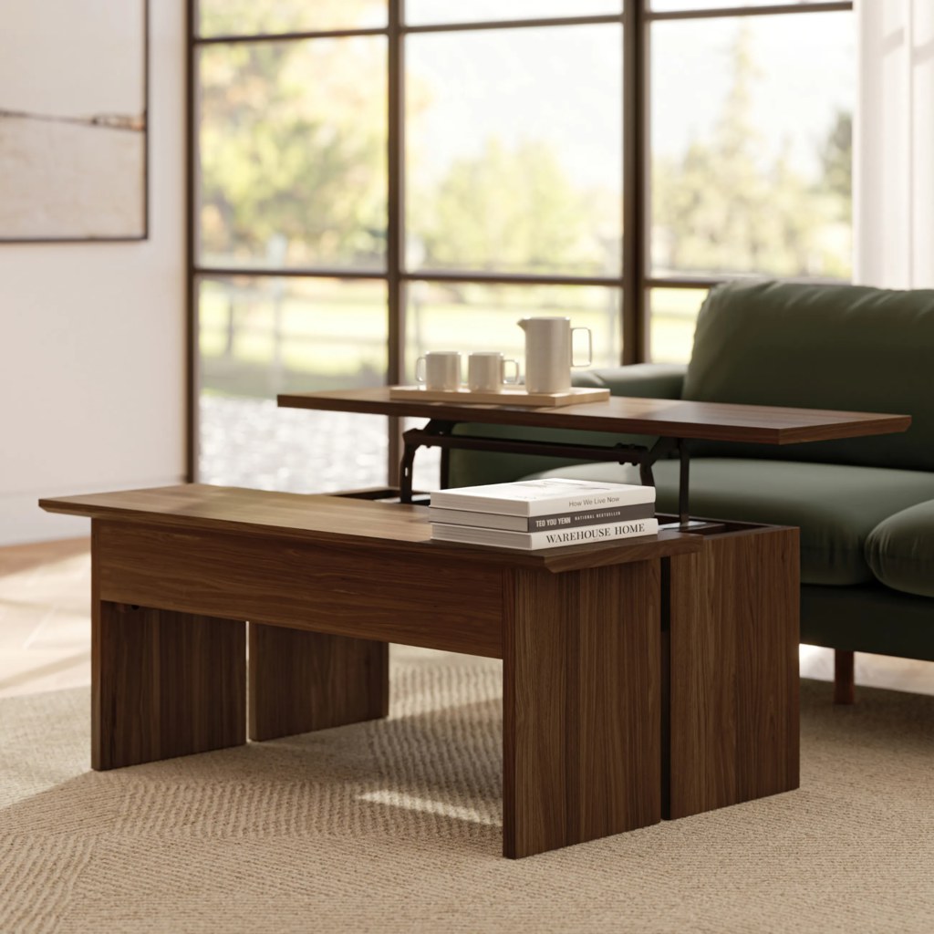 Lift-top wooden coffee table with storage compartments in a modern living room featuring a sofa, books, and natural window lighting.