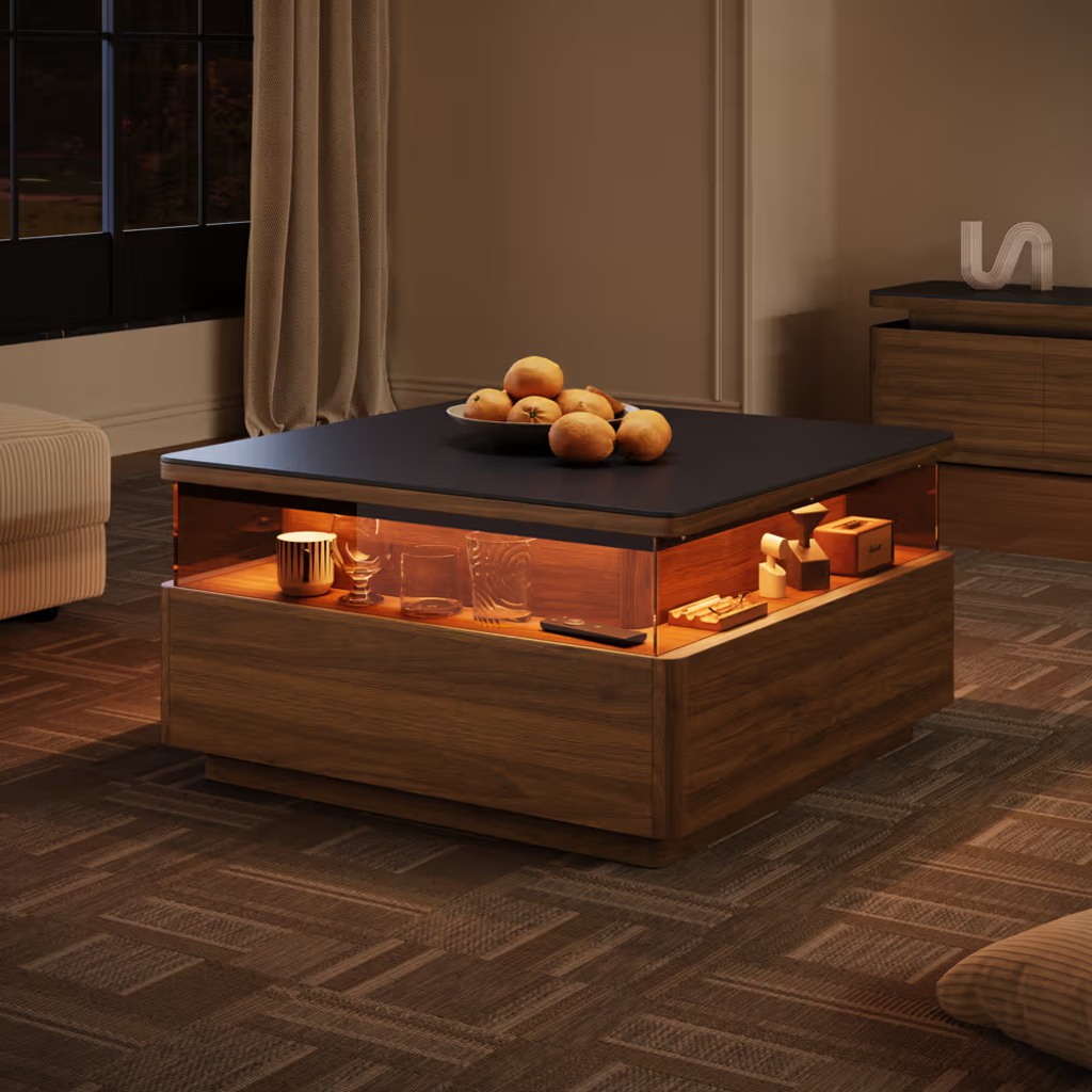 Square wood LED coffee table with warm illuminated display storage, dark tabletop, and decorative objects in a modern living room.