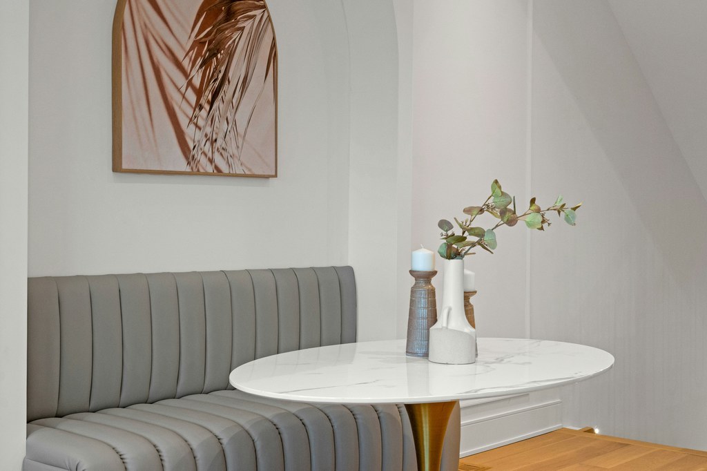 Modern dining nook with a curved upholstered banquette and round marble dining table.