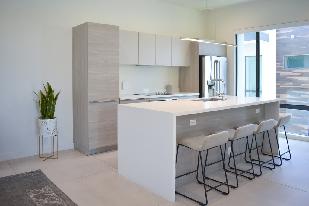 Bright modern kitchen island with four upholstered counter stools and black metal frames.