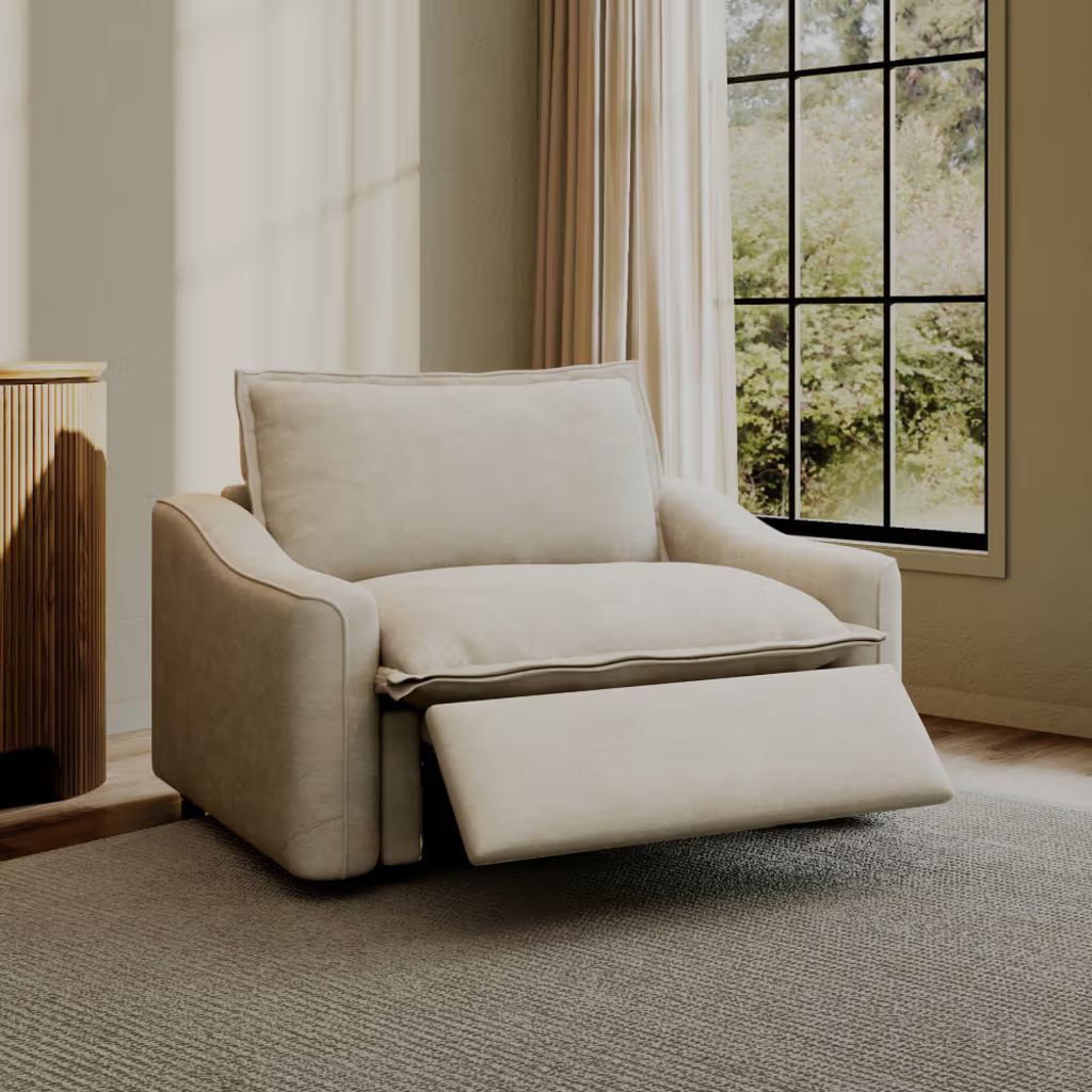 Cream upholstered power bedroom recliner with extended footrest beside a large window.