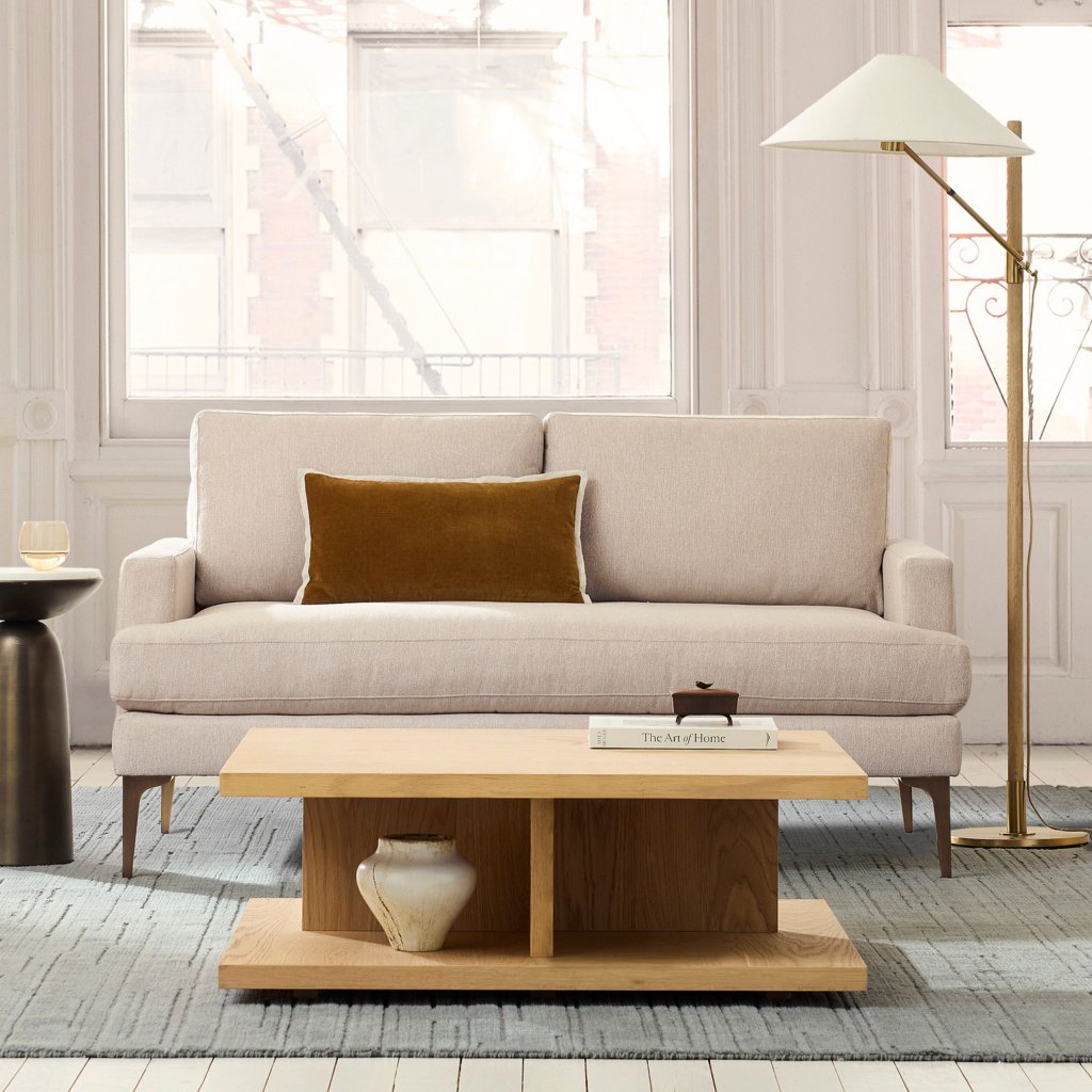 Beige bench-seat sofa with one continuous cushion, slim arms, and a wood coffee table in a bright living room.