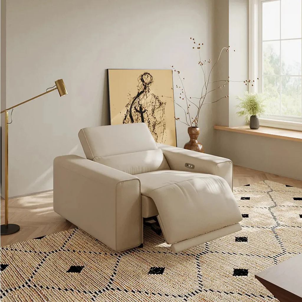 Cream leather power recliner with an extended footrest and adjustable headrest in a modern living room.