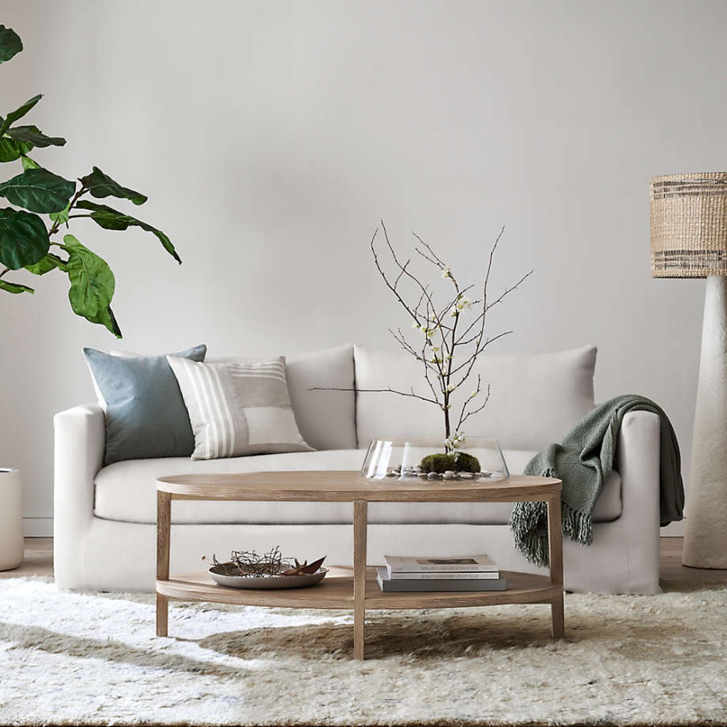 White sofa with neutral pillows, green throw, and wood coffee table in a bright living room