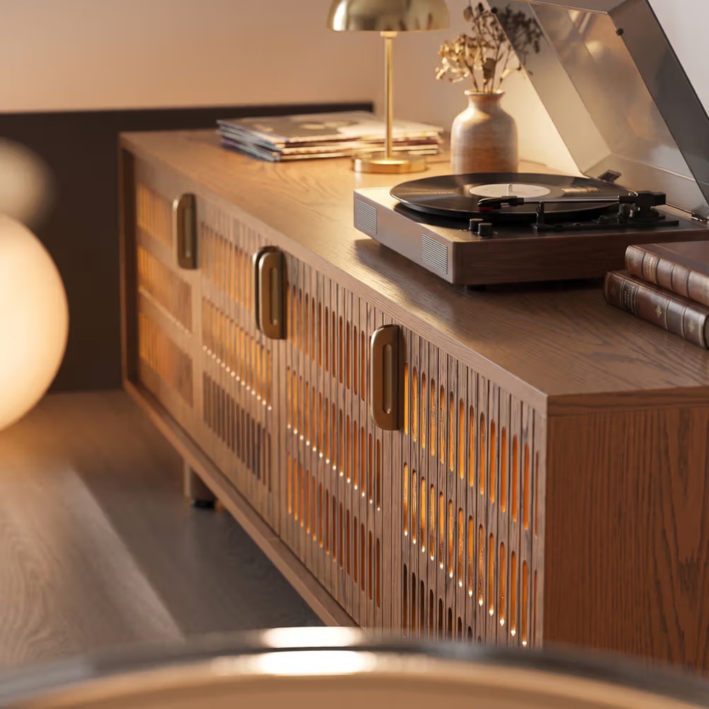 Turntable playing a vinyl record on a warm walnut slatted media console with ambient lighting.