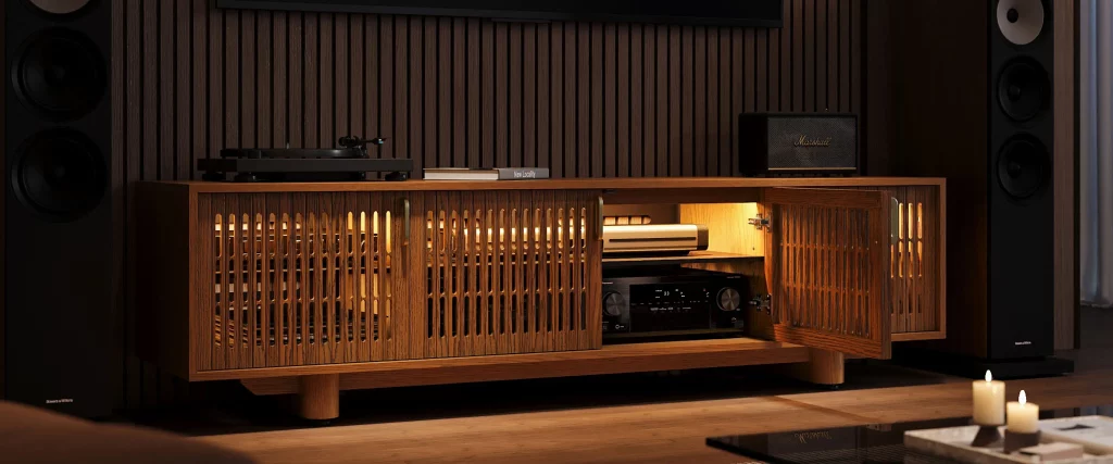 Walnut media console with slatted doors, turntable, visible AV equipment, and floor-standing speakers in a dark listening room.