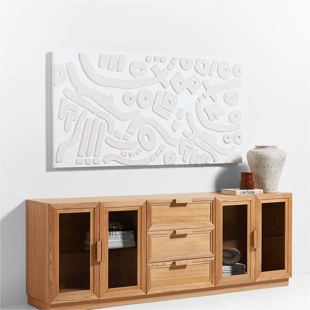 Natural wood media console with glass-front cabinets and three center drawers in a bright modern interior.