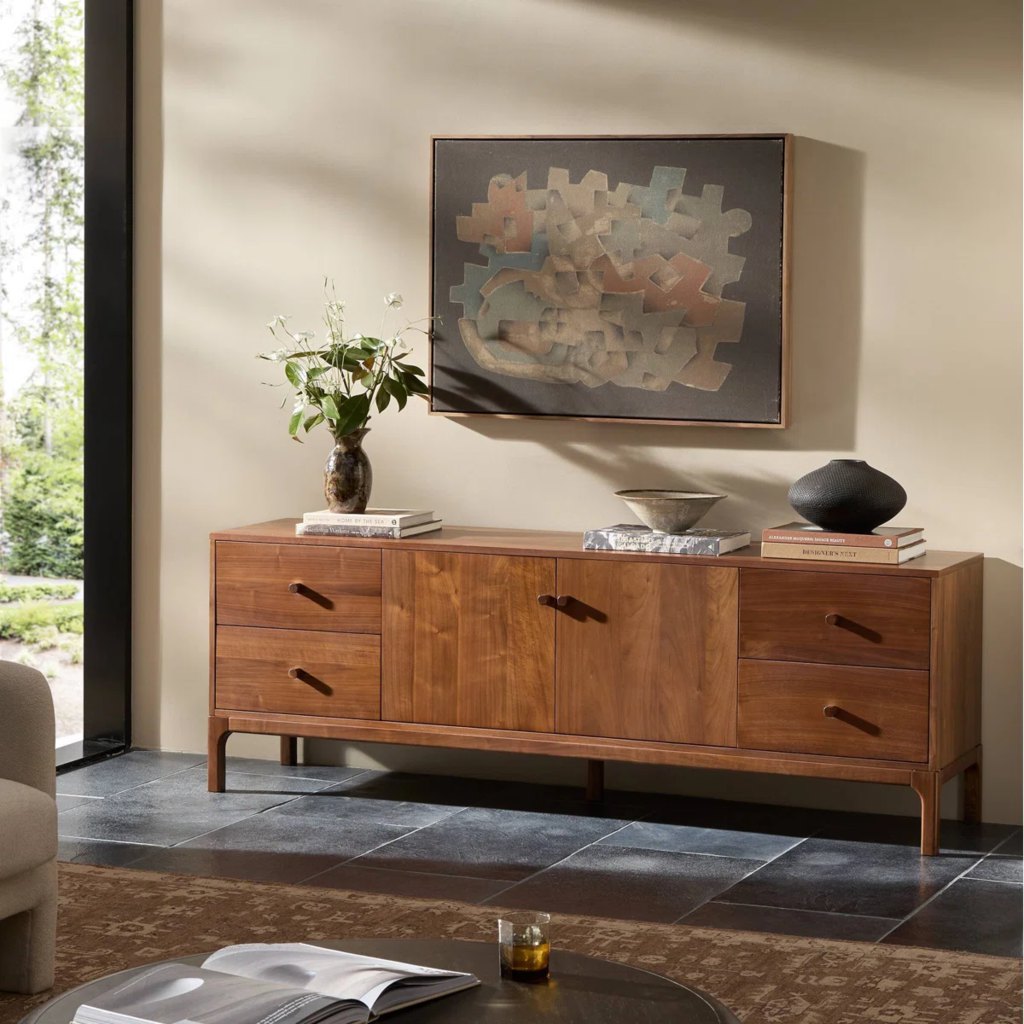Walnut media console with four drawers and central cabinet storage in a sunlit modern living room.