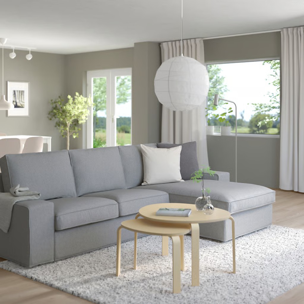 Gray chaise sectional sofa in a bright modern living room with nesting coffee tables.