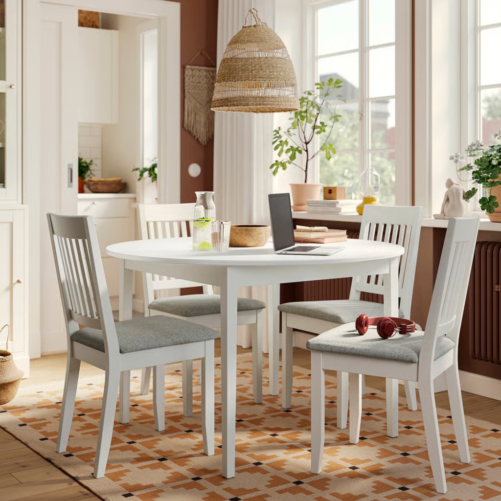 Round white dining table with four separate legs and open center space in a bright breakfast room.