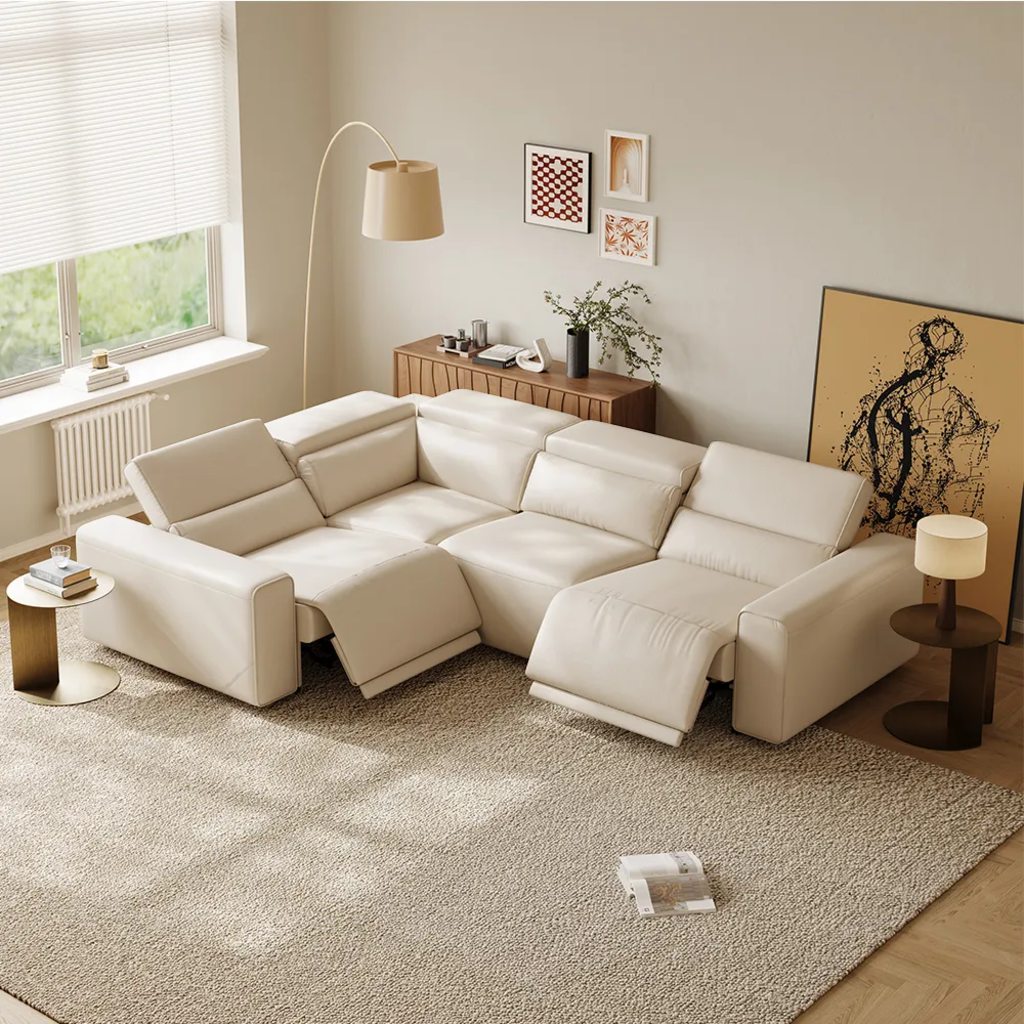 Cream L-shaped power reclining sectional with extended footrests in a bright living room with a large rug and side tables.