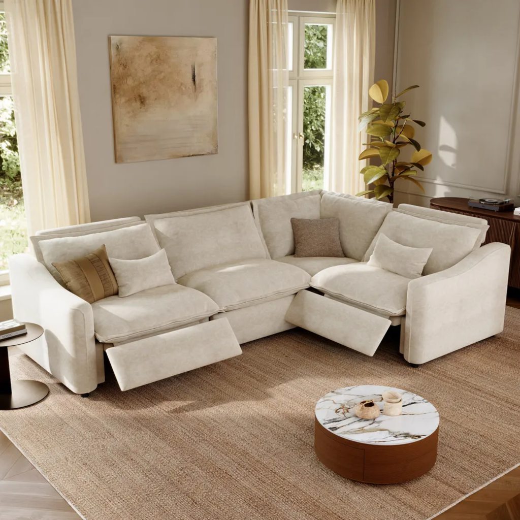 Cream L-shaped power reclining sectional with two extended footrests and a round coffee table in a bright living room.