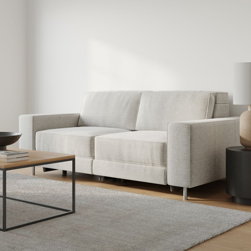 Light gray two-seat reclining sofa in a minimalist living room with a coffee table, area rug, and floor lamp.