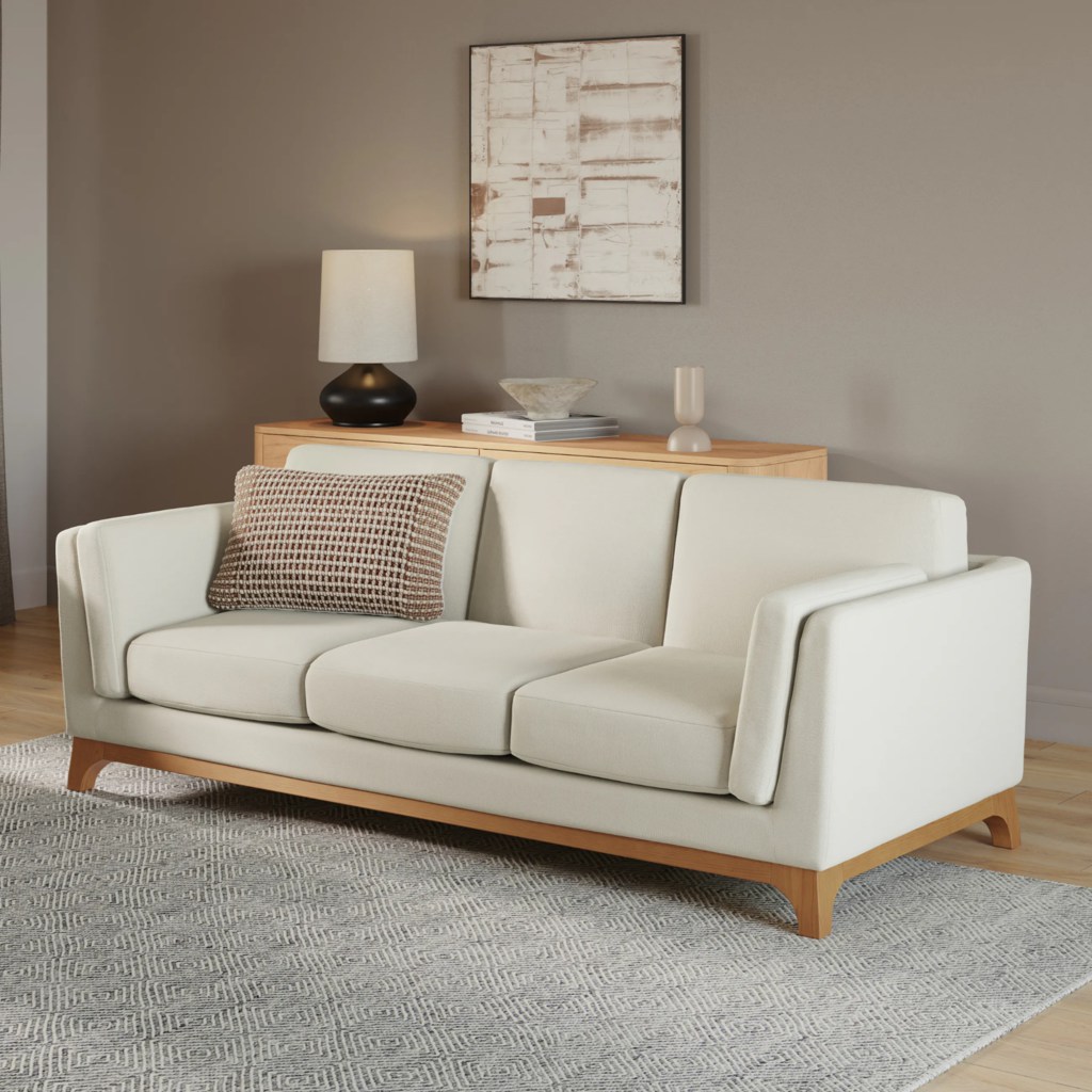 Cream three-seat sofa with separate cushions and wood trim in a neutral shared apartment living room.