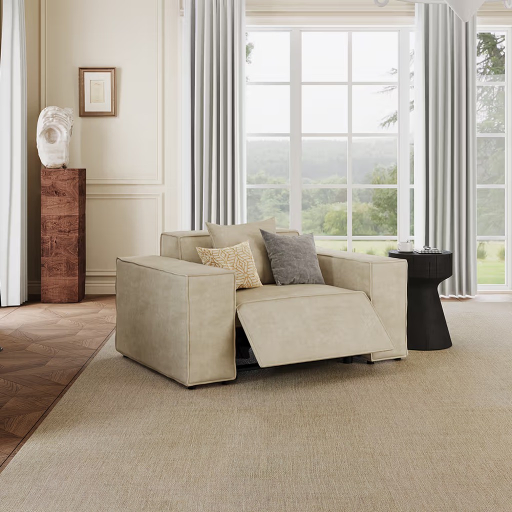 Beige power recliner chair with extended footrest in a bright modern living room.
