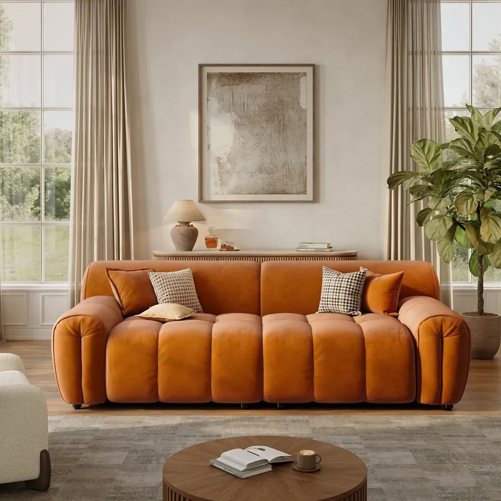 Orange channel-tufted low-profile sofa with rounded arms in a bright modern living room.
