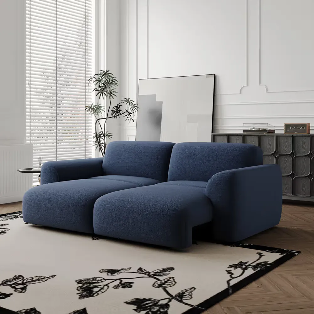 Navy blue loveseat in a bright modern living room with white walls, patterned rug, and dark storage cabinet.