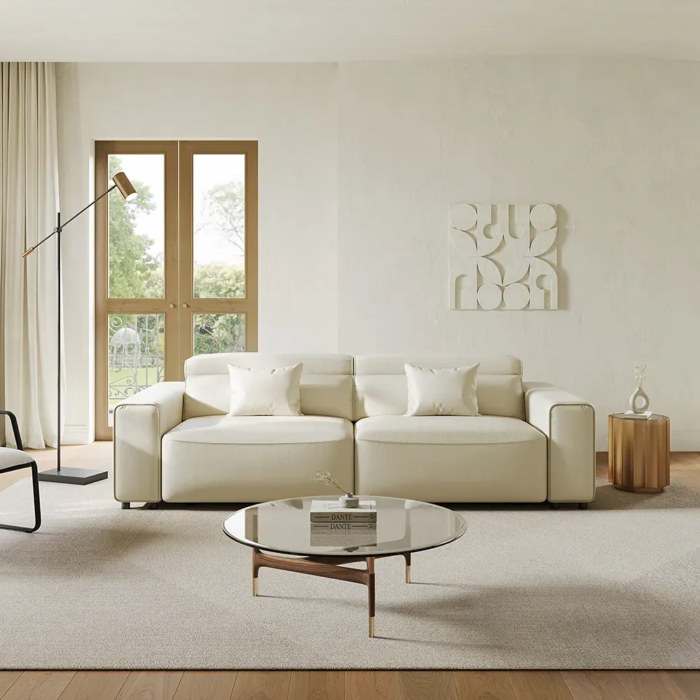 Light-colored faux leather sofa in a bright modern living room with a glass coffee table and warm wood accents.