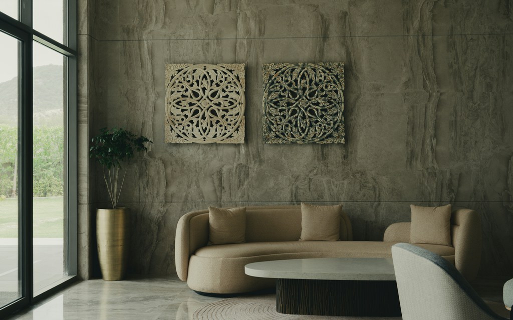 Curved beige sofa in a modern living room with marble walls, large windows, and a minimalist coffee table.