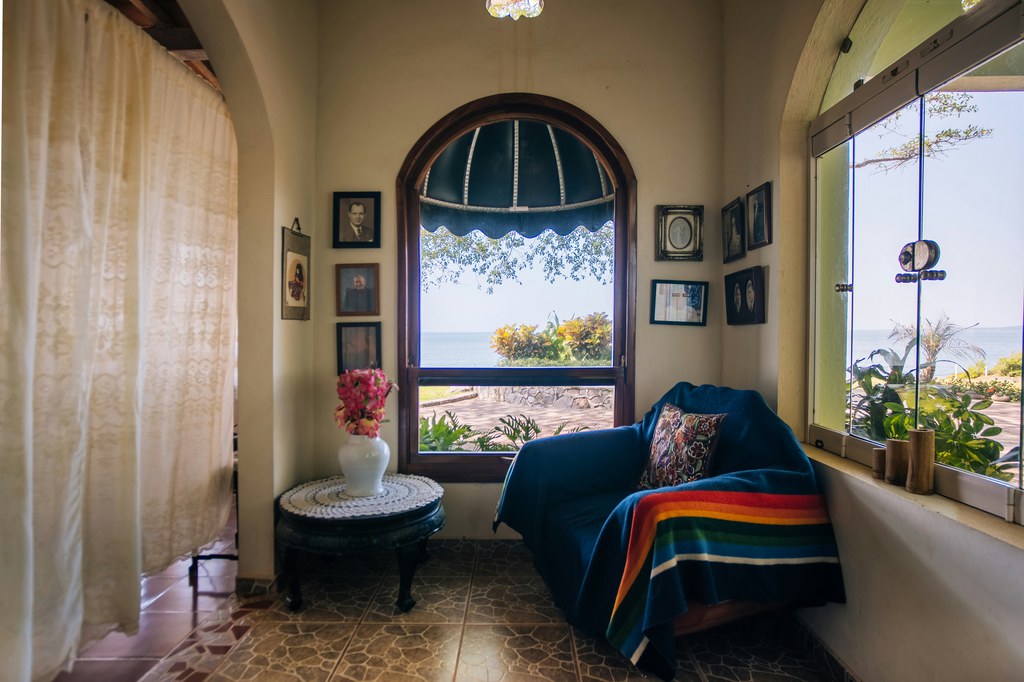 Cozy armchair in a bright reading nook with ocean views through large windows.