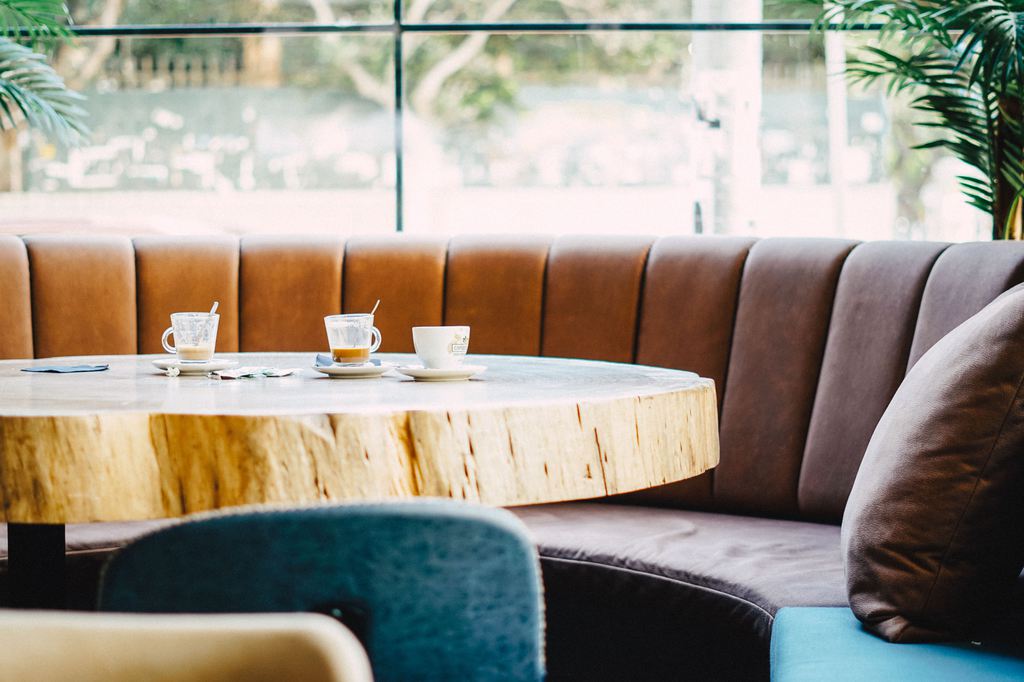 Curved upholstered banquette seating with a round wood dining table in a bright modern dining space.