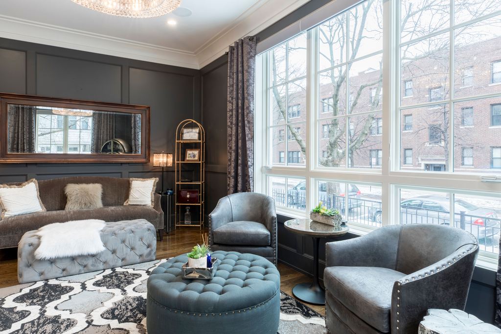Gray tufted round ottoman with matching lounge chairs in an elegant living room.