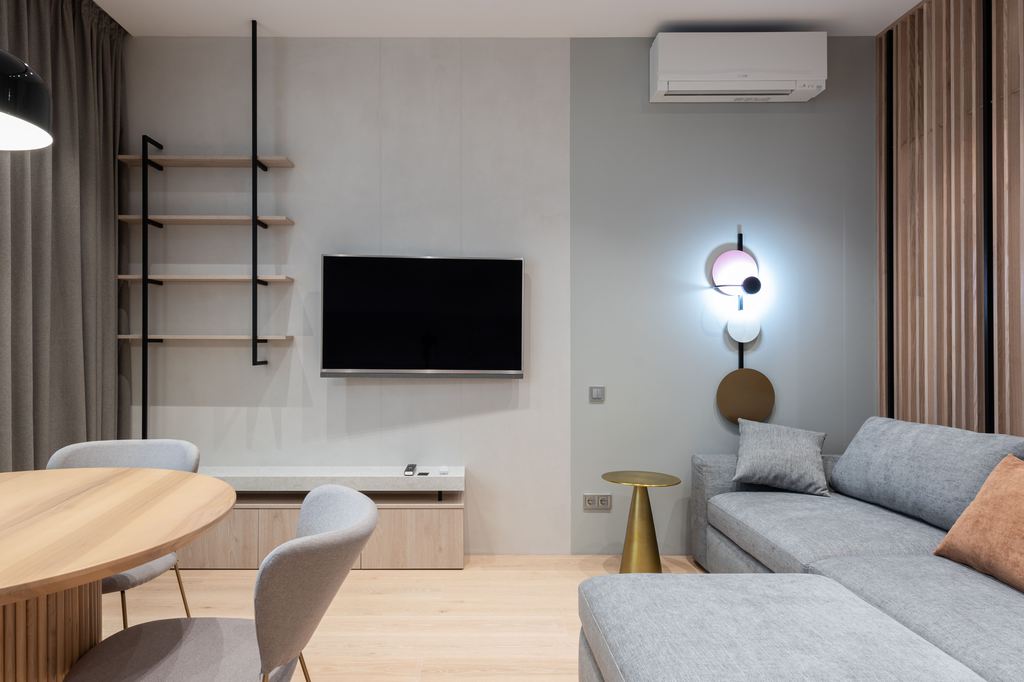 Gray chaise sectional facing a wall-mounted TV in a compact modern living and dining room.