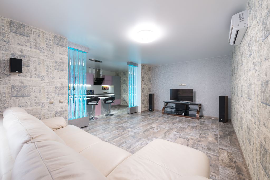 Spacious media room with a white sectional sofa facing a TV and floor-standing speakers.