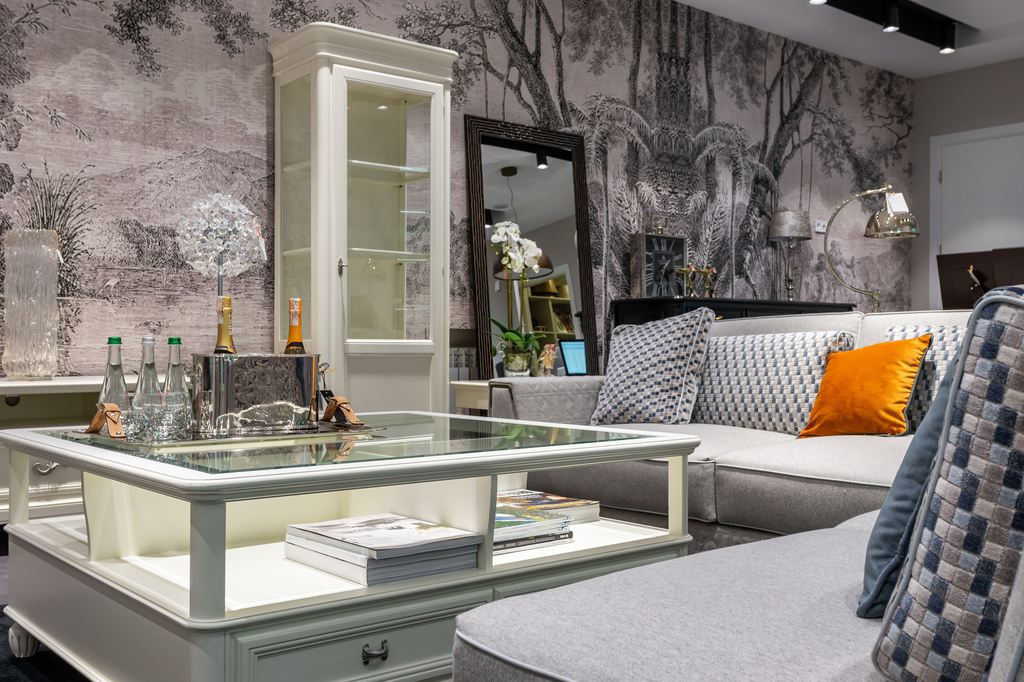 White glass-top coffee table with built-in shelf storage in a contemporary living room with gray sectional sofas.