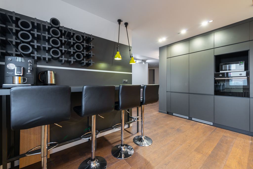 Modern kitchen bar with four black adjustable stools on chrome pedestal bases.