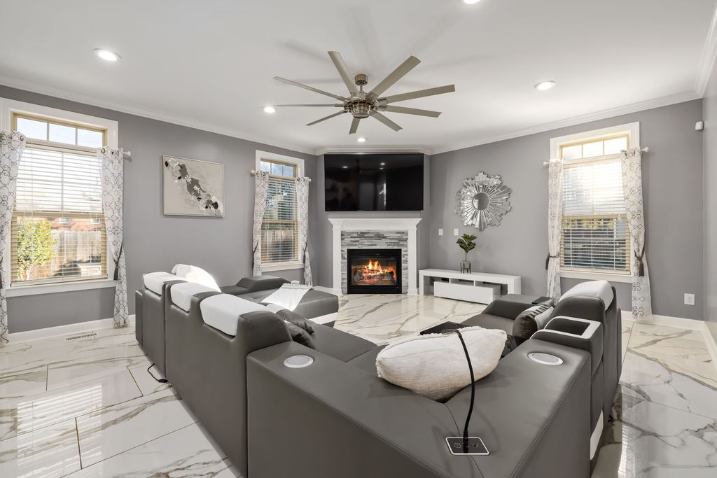 Gray reclining sectional sofas facing a TV and fireplace in a bright modern living room.