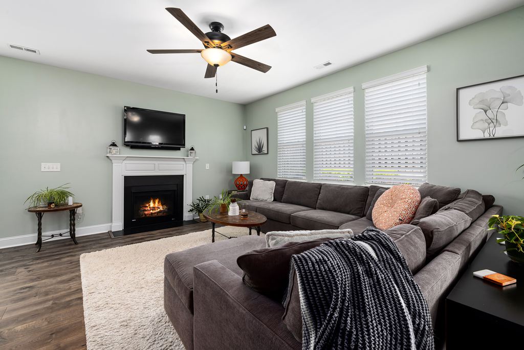 Large gray U-shaped sectional facing a wall-mounted TV and fireplace in a bright family media room.