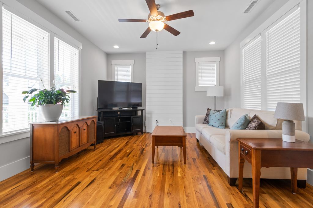 Modern living room with wood furniture, a white sofa, TV stand, and coffee table on polished hardwood flooring.